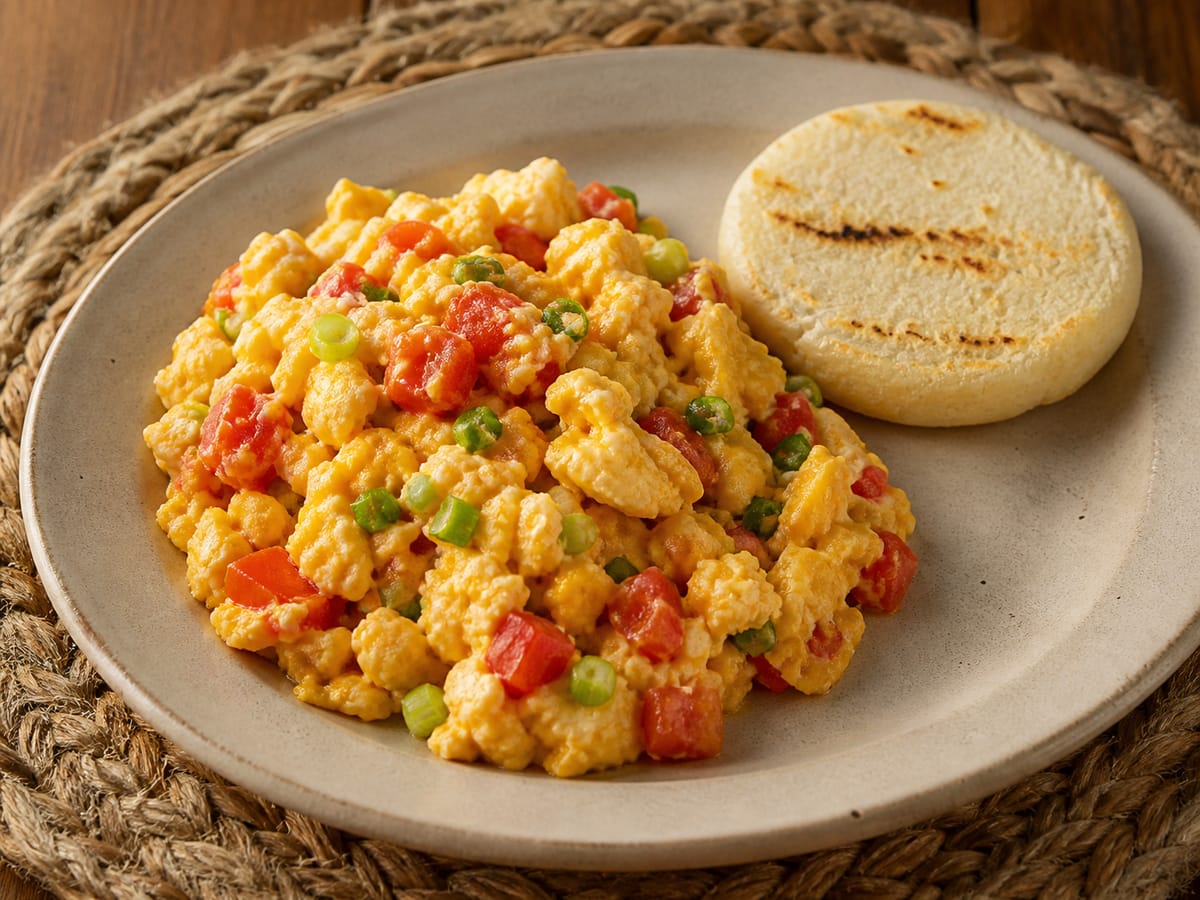 Huevos pericos colombianos con tomate y cebolla larga servidos con arepa